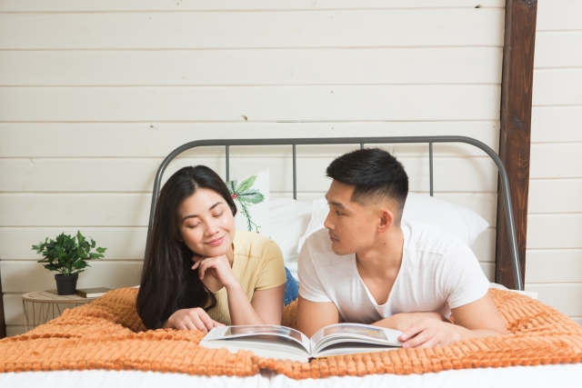 ベッドに横たわり本を読むカップル
